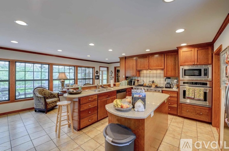 A kitchen with wooden cabinets and a large island in the middle.