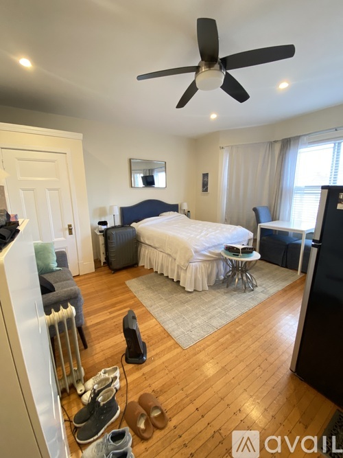 A bedroom with a bed, a chair, a table, and a ceiling fan.