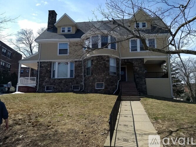 A large house with a stone wall and a covered porch.