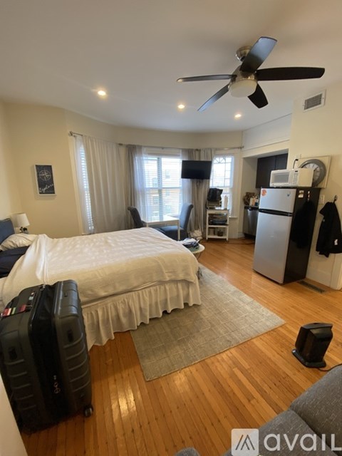 A bedroom with a bed, a fan, and a suitcase.
