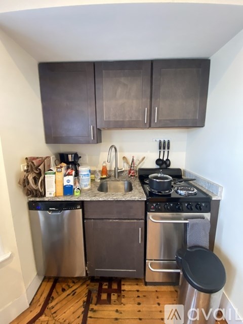 A small kitchen with a stove, sink, and cabinets.