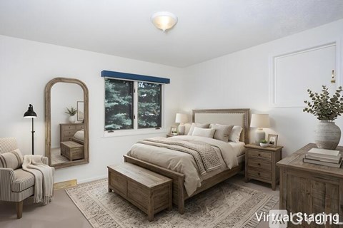 A bedroom with a large bed, a chair, and a mirror.
