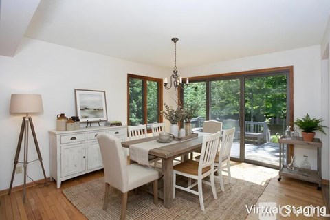 A dining room with a table set for four and a chandelier hanging from the ceiling.