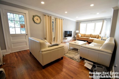 A living room with a clock on the wall and a couch.