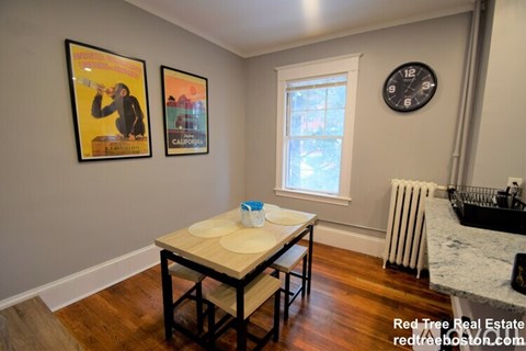A dining room with a table and chairs and two posters on the wall.