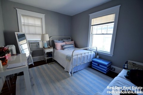 A bedroom with a bed, desk, and chair.