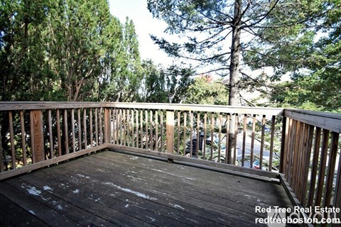 A wooden deck with a railing and trees in the background.