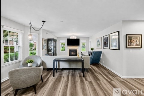 A living room with a grey chair, a black coffee table, and a television on the wall.