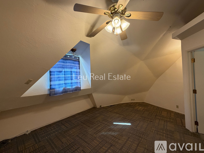 A room with a ceiling fan and a window with a view of a building outside.