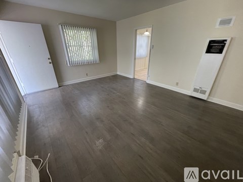 A spacious room with wooden flooring and a white door.