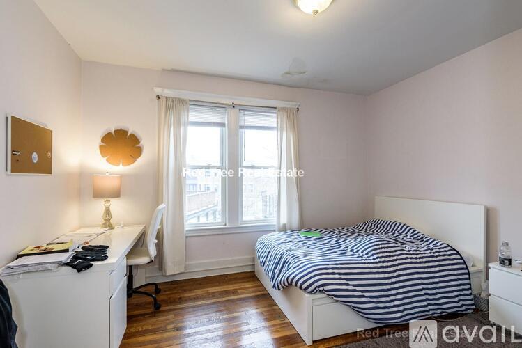 A bedroom with a bed, desk, and window.