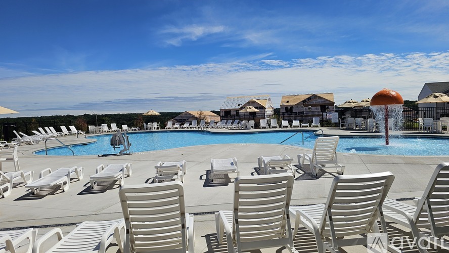 A pool with sun loungers in the foreground and a building in the background.