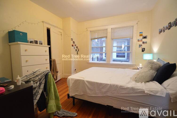 A bedroom with a bed, nightstand, and window.