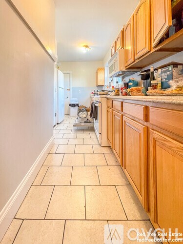 A kitchen with wooden cabinets and a tiled floor.