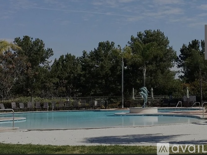 A pool surrounded by trees and a fence.