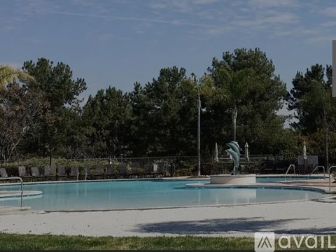 A pool surrounded by trees and a fence.