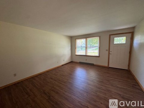 A room with wooden flooring and a window with a view of trees.