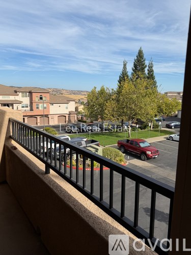 A balcony overlooks a parking lot and a building.