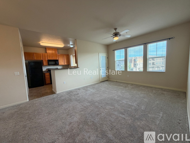 A spacious living room with a carpeted floor and a ceiling fan.