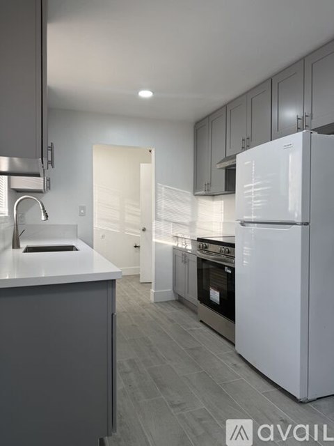 A modern kitchen with a white fridge and a grey counter.