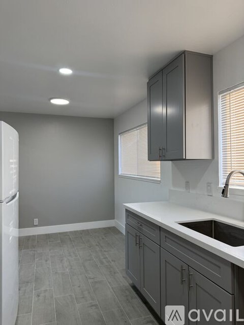 A kitchen with grey cabinets and a white fridge.
