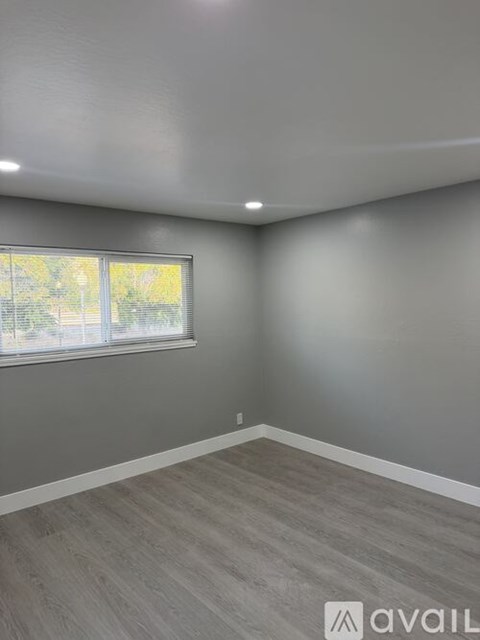 A room with grey walls and a window with a view of trees outside.