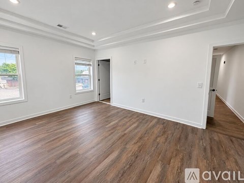A spacious room with wooden flooring and white walls.