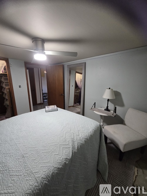A bedroom with a bed, a chair, and a lamp.