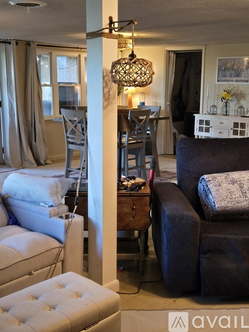 A living room with a white couch and a brown chair.
