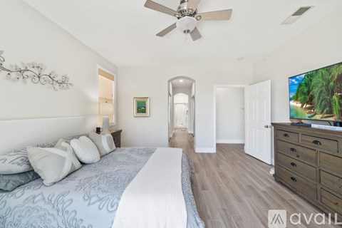 A bedroom with a large bed and a ceiling fan.