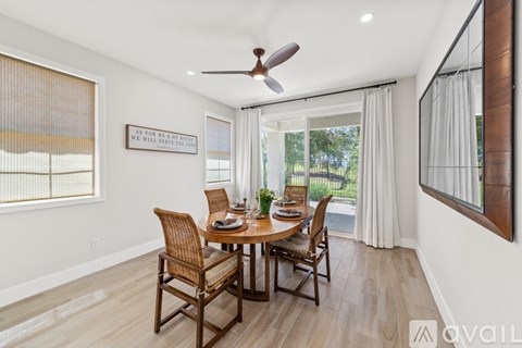 A dining room with a table set for four and a ceiling fan.