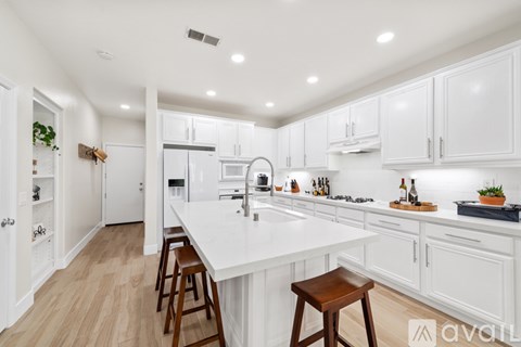 A white kitchen with wooden floors and white cabinets.