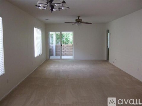A spacious room with a ceiling fan and sliding glass doors.