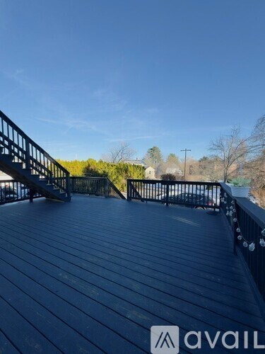 A wooden deck with a metal railing and steps leading to a grassy area.