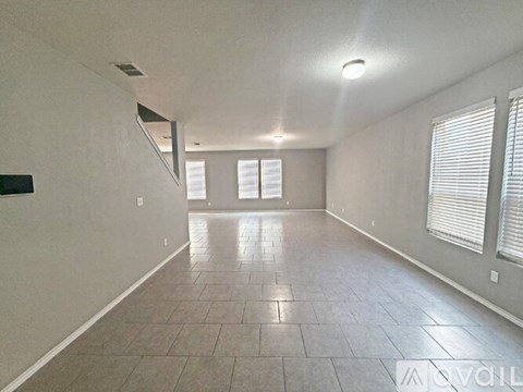 A spacious room with tiled flooring and a staircase on the left side.