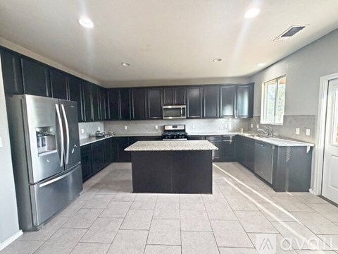 A kitchen with black cabinets and a granite countertop.