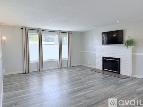 A living room with a fireplace and a television on the wall.