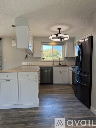 A kitchen with white cabinets and a black refrigerator.