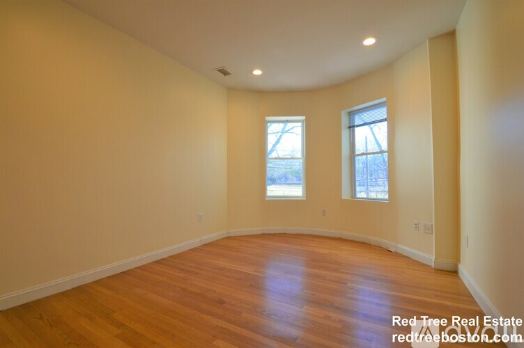 A room with wooden floors and two windows.