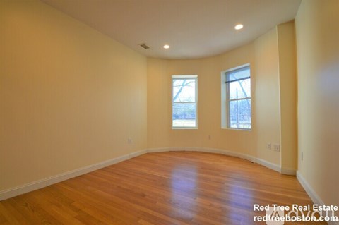A room with wooden floors and two windows.