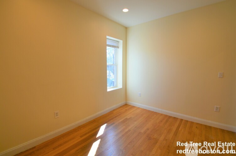 A room with wooden flooring and a window letting in light.