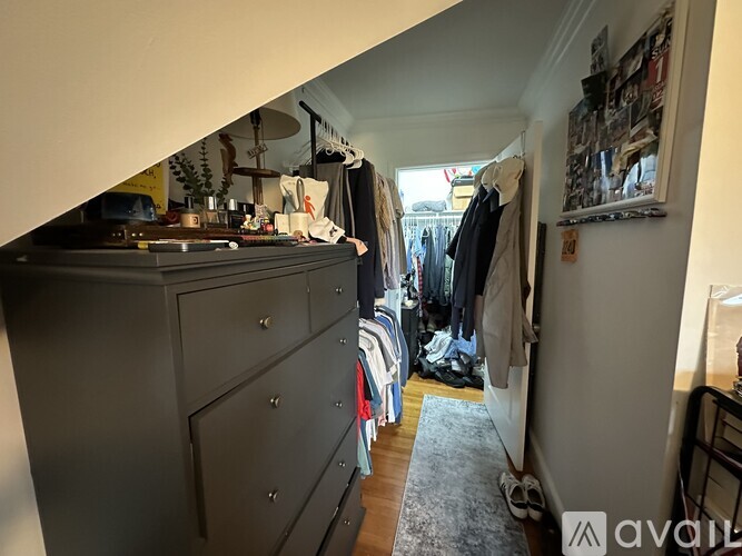 A room with a grey dresser and a rack of clothes.