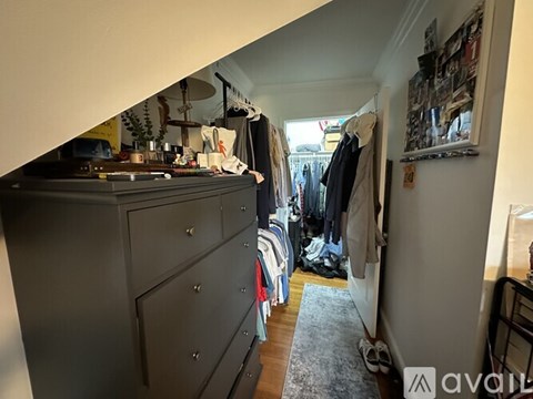 A room with a grey dresser and a rack of clothes.
