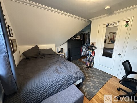 A bedroom with a bed, chair, and a bookshelf.