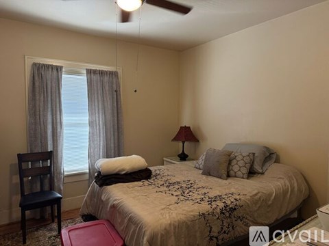A bedroom with a bed, chair, and window.