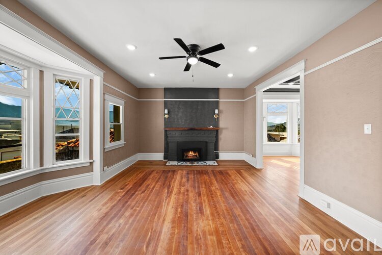 A spacious room with a fireplace and a ceiling fan.