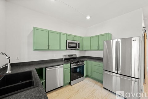 A kitchen with green cabinets and a black counter top.