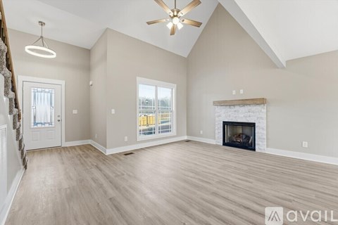 A spacious living room with a fireplace and a ceiling fan.
