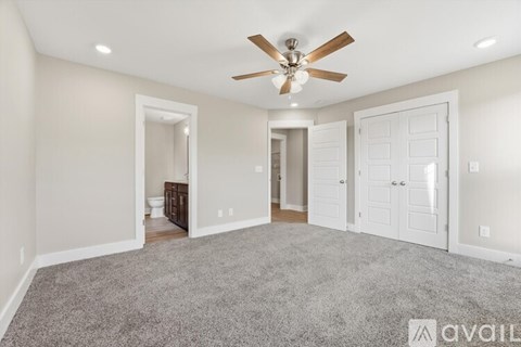 A spacious room with a ceiling fan and carpeted floor.