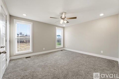 A spacious room with a ceiling fan and a large window overlooking a field.
